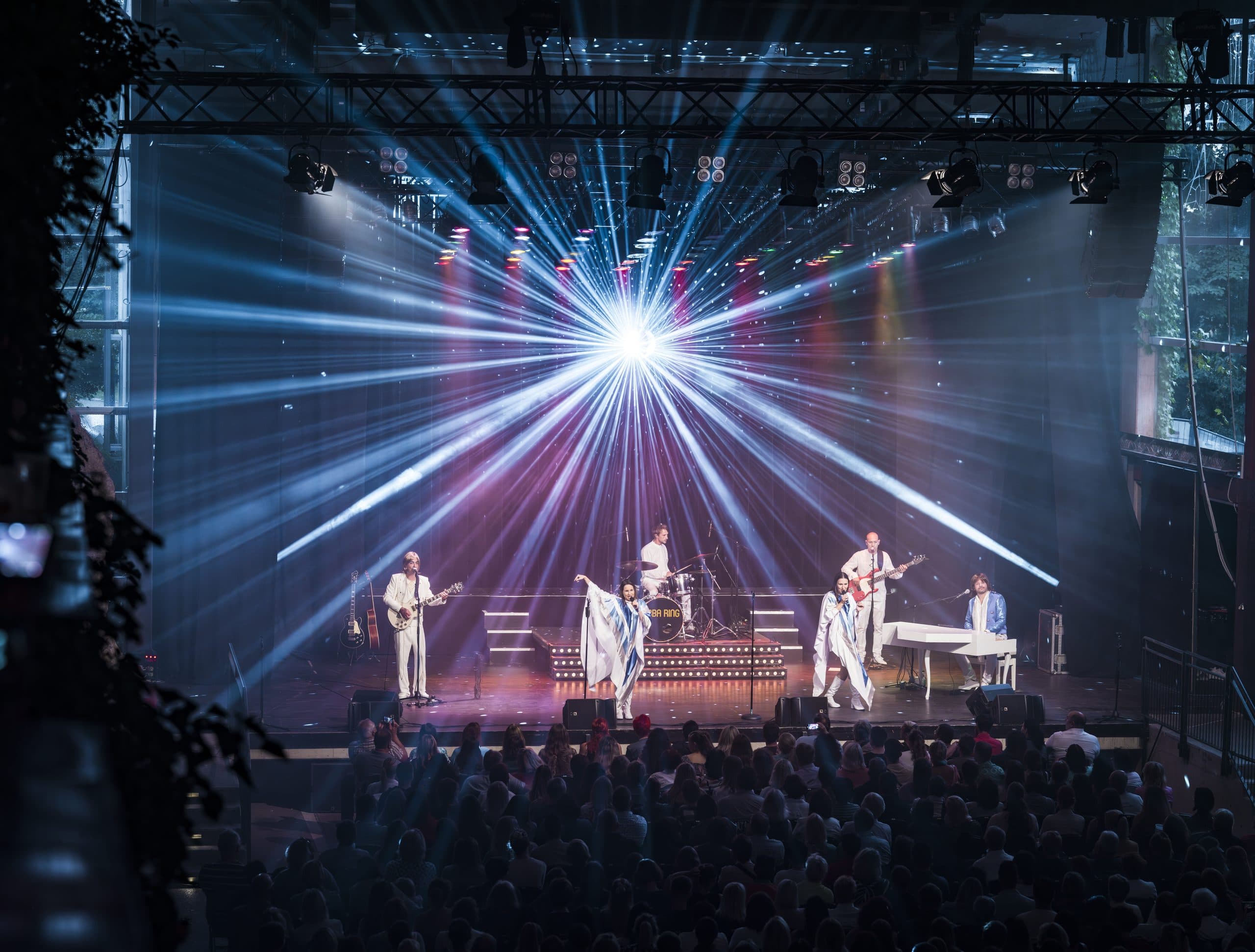 Open-Air-Bühne mit Traversen, Lichtstrahlen, Publikum von hinten